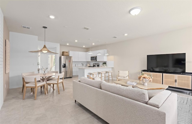 living area featuring baseboards, visible vents, and recessed lighting