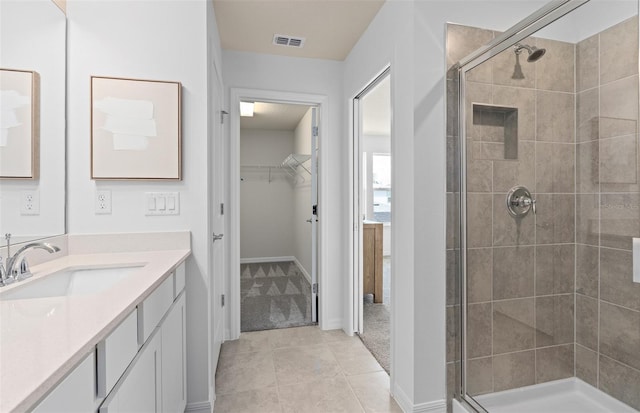 full bathroom with vanity, a shower stall, visible vents, and a walk in closet