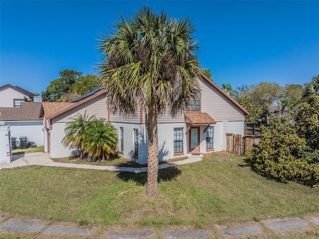 view of front facade with driveway, roof with shingles, a front yard, and fence