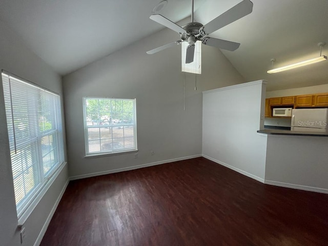 unfurnished living room with vaulted ceiling, dark wood-style floors, baseboards, and ceiling fan