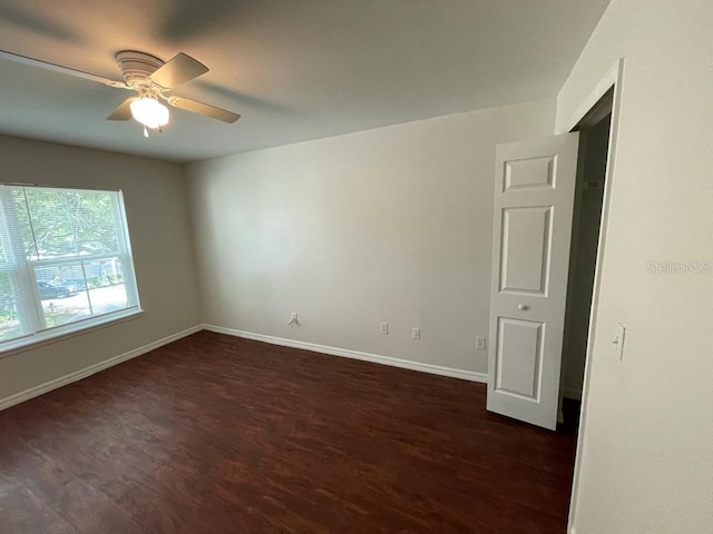 spare room featuring dark wood finished floors, baseboards, and ceiling fan