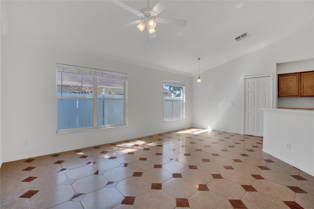 spare room featuring lofted ceiling, visible vents, ornamental molding, a ceiling fan, and baseboards