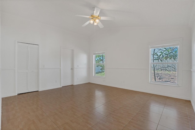 empty room featuring lofted ceiling, ceiling fan, and baseboards