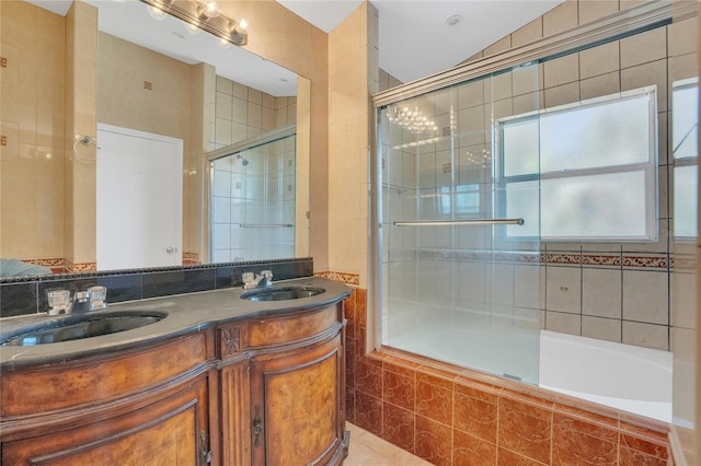 bathroom with tile walls, a sink, tiled shower / bath combo, and double vanity