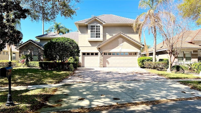 traditional-style house featuring stone siding, stucco siding, a tiled roof, and decorative driveway