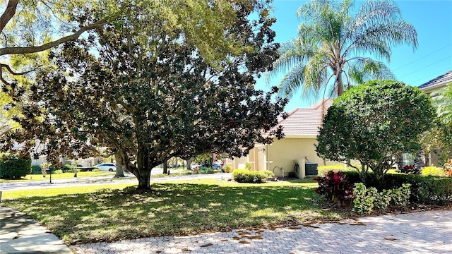 view of side of home featuring stucco siding, central air condition unit, a lawn, and a tile roof