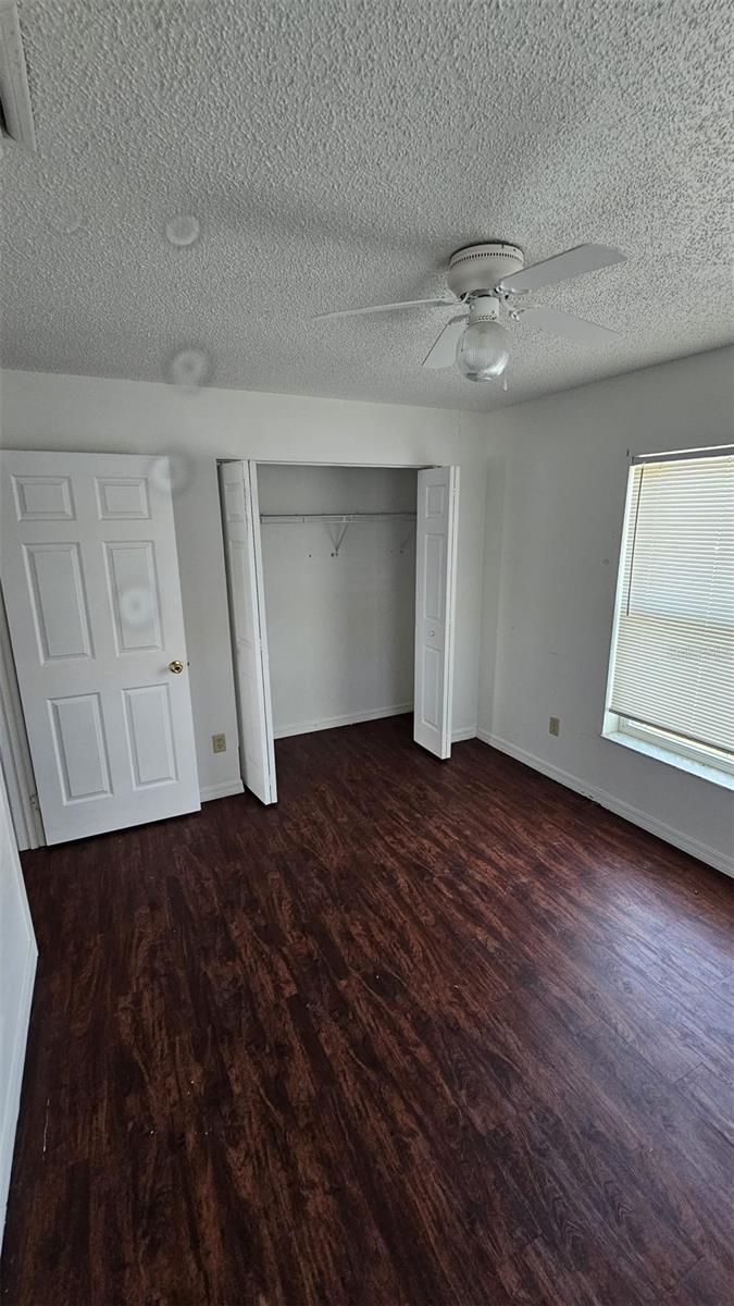 unfurnished bedroom with baseboards, a closet, a ceiling fan, and wood finished floors