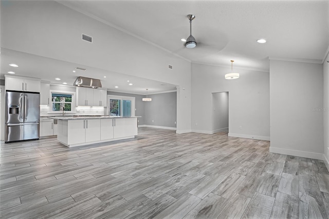 kitchen featuring light wood-type flooring, visible vents, open floor plan, stainless steel fridge, and white cabinets