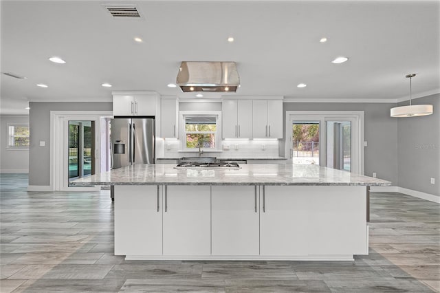 kitchen featuring a spacious island, visible vents, decorative backsplash, white cabinets, and stainless steel appliances