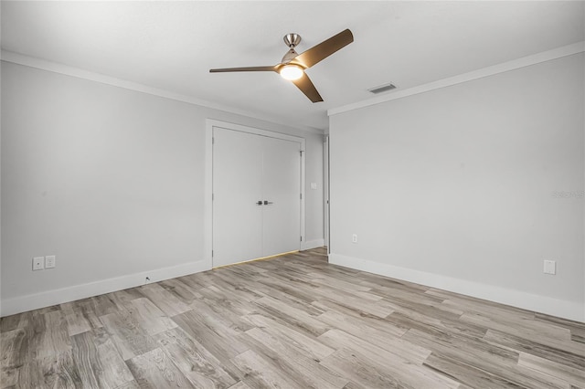 spare room with visible vents, crown molding, light wood-type flooring, and baseboards