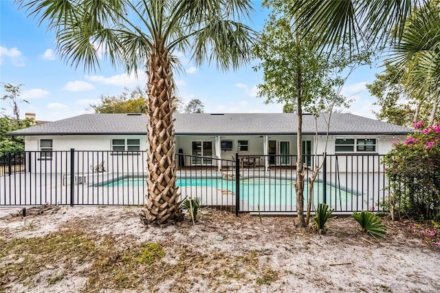 rear view of property featuring a patio area, stucco siding, a fenced in pool, and fence