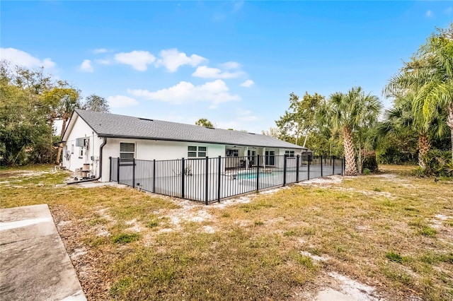 rear view of property featuring fence, a fenced in pool, stucco siding, a patio area, and a lawn