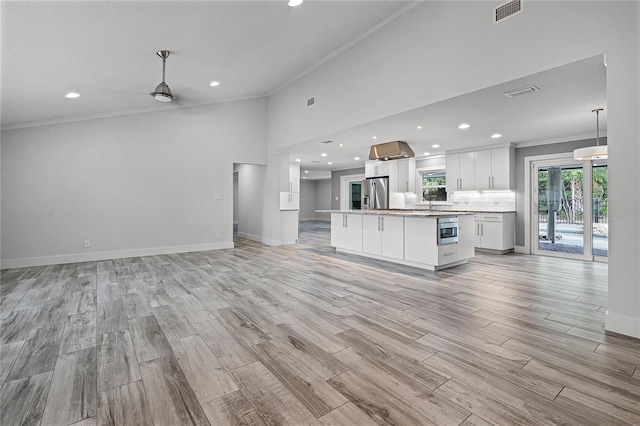 unfurnished living room with visible vents, light wood-style flooring, crown molding, and baseboards