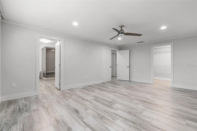 spare room with recessed lighting, crown molding, light wood-type flooring, and baseboards