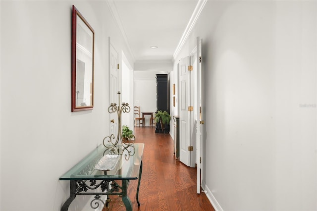 hall featuring ornamental molding, dark wood finished floors, and baseboards