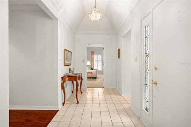 foyer featuring a chandelier, light tile patterned flooring, baseboards, vaulted ceiling, and crown molding