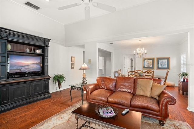 living area featuring ceiling fan with notable chandelier, dark wood-type flooring, visible vents, baseboards, and crown molding