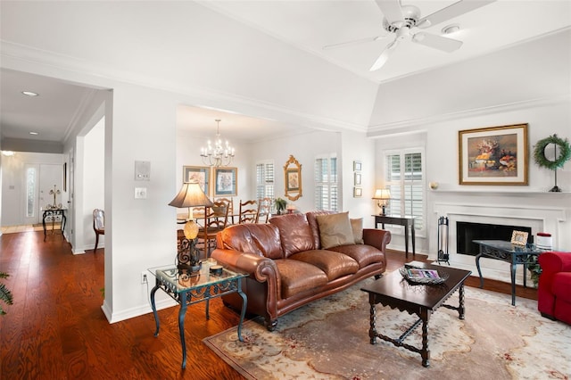 living area featuring baseboards, ornamental molding, wood finished floors, a fireplace, and ceiling fan with notable chandelier