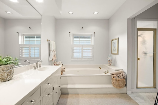 bathroom with a wealth of natural light, a garden tub, vanity, and recessed lighting