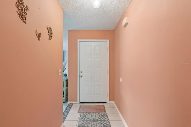 doorway with light tile patterned floors, baseboards, and a textured ceiling