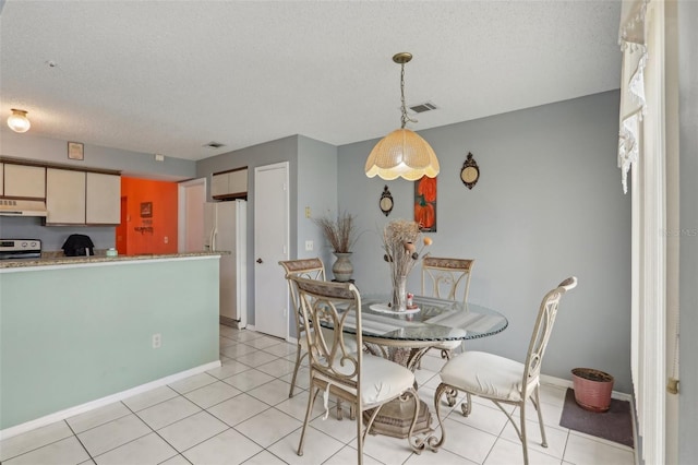 dining area featuring light tile patterned floors, visible vents, baseboards, and a textured ceiling