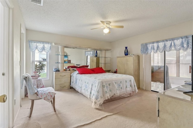 carpeted bedroom featuring access to exterior, visible vents, a textured ceiling, and ceiling fan