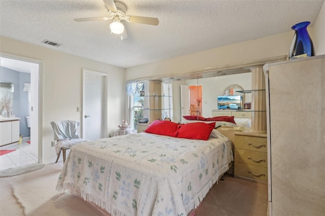 bedroom featuring light carpet, visible vents, a textured ceiling, and a ceiling fan