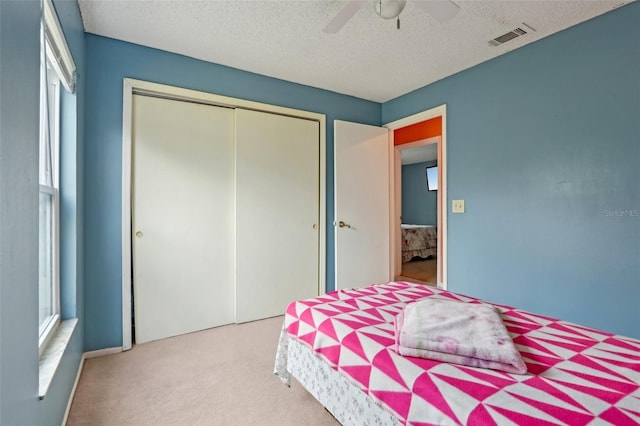 bedroom with visible vents, a textured ceiling, a closet, carpet floors, and ceiling fan