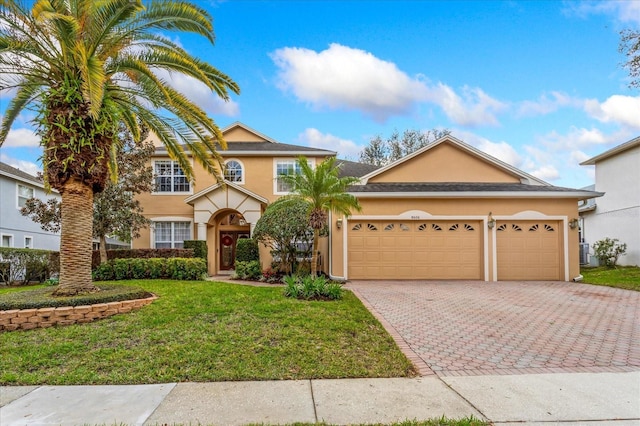 view of front of house featuring an attached garage, decorative driveway, a front yard, and stucco siding