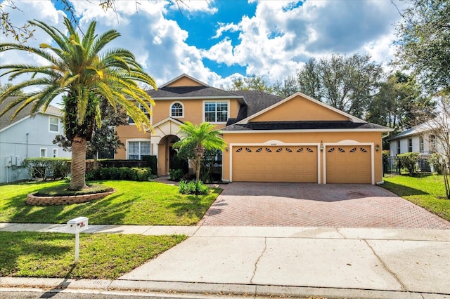 view of front of house with a garage, fence, decorative driveway, stucco siding, and a front lawn