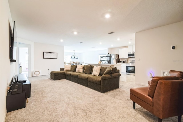 living area with baseboards, recessed lighting, visible vents, and light colored carpet