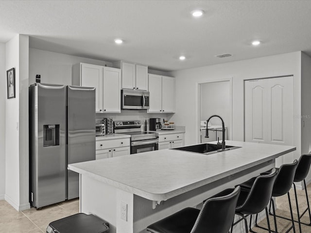 2925 SW 172nd Lane Rd, Ocala, FL 34473 - kitchen with white cabinetry, a kitchen island with sink, a sink, appliances with stainless steel finishes, and a kitchen bar