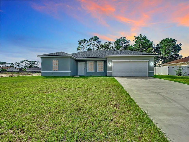 view of front of property with concrete driveway, a lawn, an attached garage, and fence