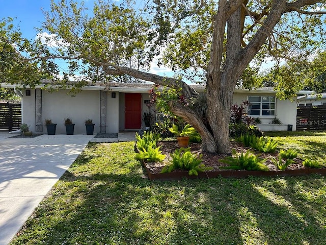 ranch-style home with a front yard, fence, and stucco siding