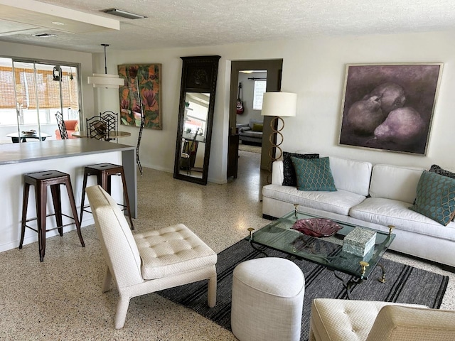 living room featuring light speckled floor, visible vents, plenty of natural light, and a textured ceiling