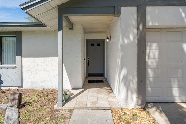 view of exterior entry featuring a garage and stucco siding