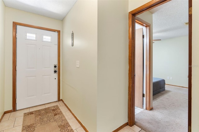 foyer entrance featuring a textured ceiling, light tile patterned flooring, and baseboards