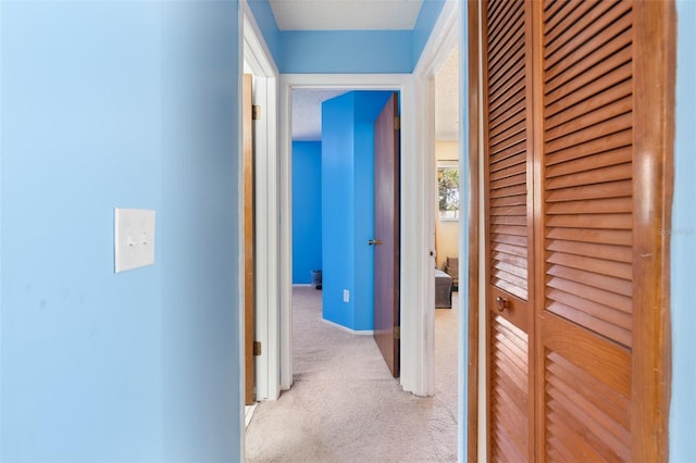 corridor featuring light carpet and baseboards