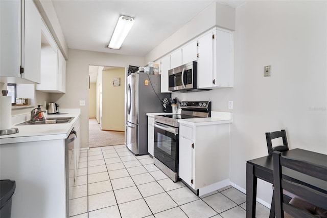 kitchen with light tile patterned floors, white cabinetry, appliances with stainless steel finishes, and light countertops