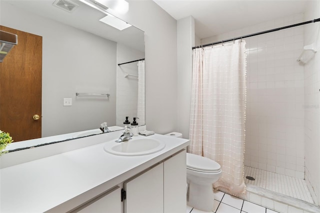 bathroom featuring toilet, vanity, visible vents, a tile shower, and tile patterned floors