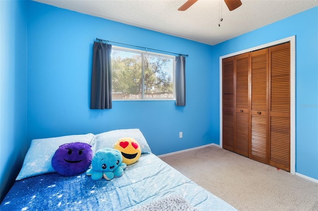 bedroom featuring baseboards, a ceiling fan, a textured ceiling, carpet flooring, and a closet