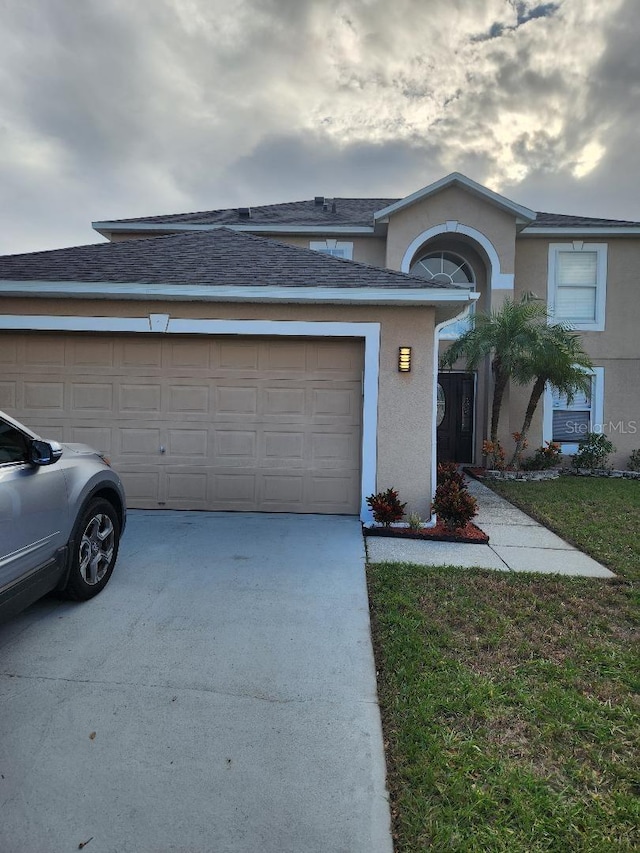 view of front of house featuring concrete driveway, an attached garage, a front yard, and stucco siding