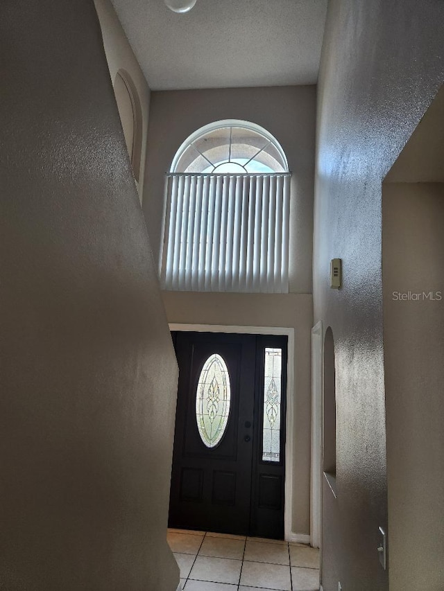 foyer entrance featuring tile patterned flooring, a textured ceiling, and a textured wall