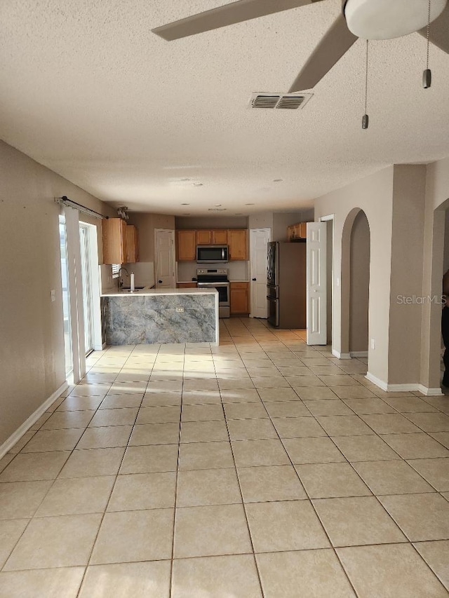 kitchen featuring a peninsula, light tile patterned floors, visible vents, and stainless steel appliances