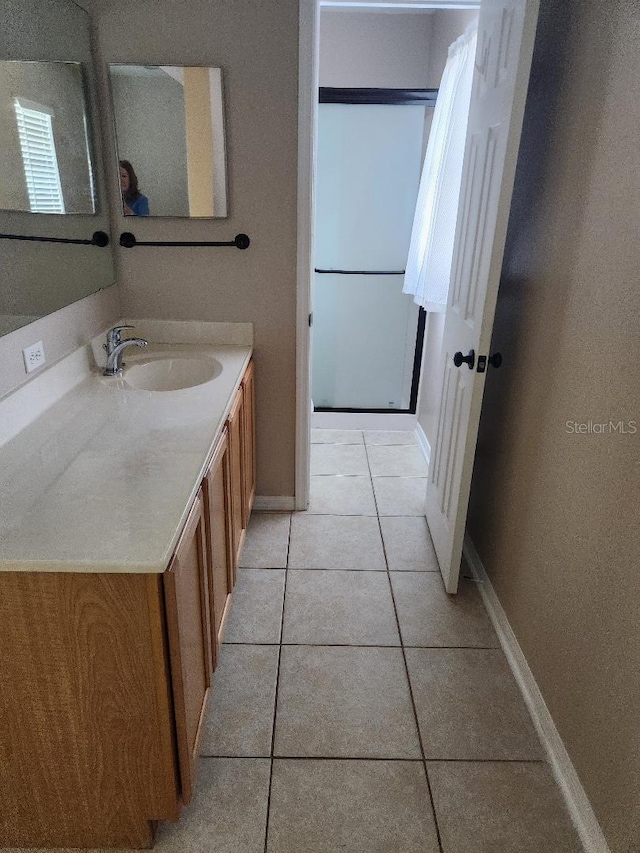 full bathroom featuring vanity, tile patterned floors, baseboards, and walk in shower