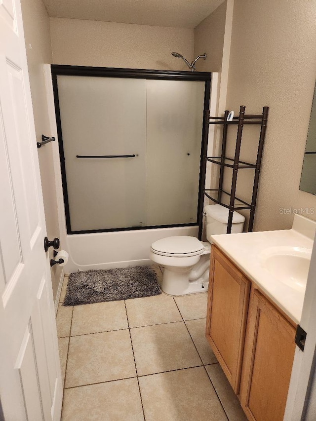 bathroom featuring tile patterned flooring, toilet, vanity, and shower / bath combination with glass door