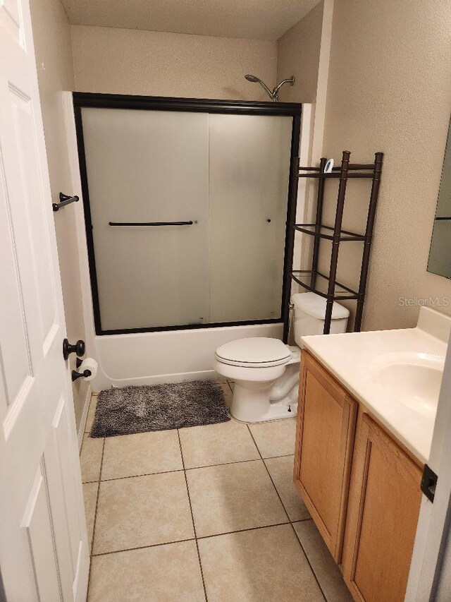 bathroom featuring shower / bath combination with glass door, toilet, vanity, and tile patterned flooring