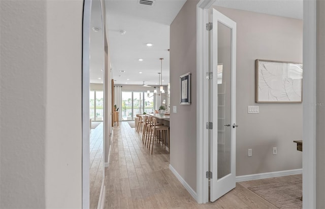 hallway with recessed lighting, baseboards, visible vents, and light wood finished floors