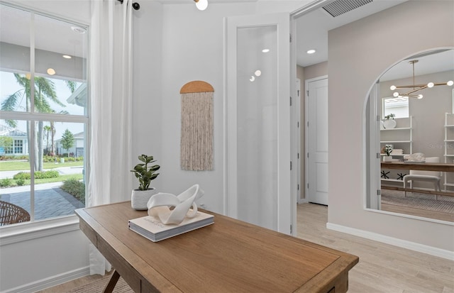 interior space featuring visible vents, arched walkways, baseboards, light wood-type flooring, and a chandelier