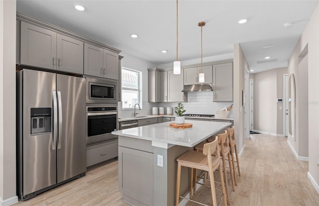 kitchen with gray cabinetry, stainless steel appliances, a sink, and under cabinet range hood